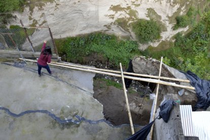 Estefanía Pabón mira a través del socavón que se formó en el patio de su casa por las erosión.