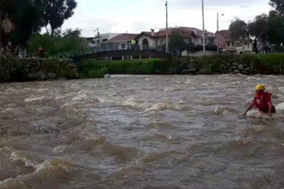 Un rescatista busca en las peligrosas aguas del Tomebamba, con ayuda de una cuerda.