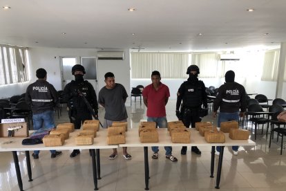 Agentes antidrogas escoltan a los dos detenidos (centro), junto a los paquetes de marihuana incautados.