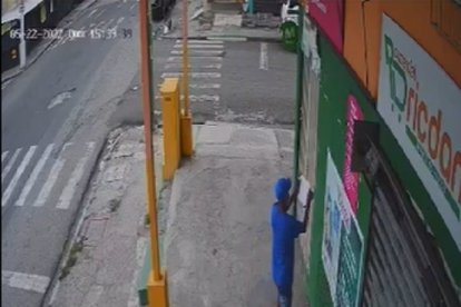 Una cámara de seguridad captó a un delincuente cuando pegaba el cartel.