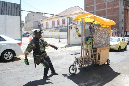 El hombre jala un coche de madera que tiene como volante la parte delantera de un triciclo.