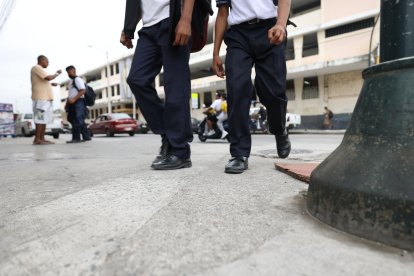 Un estudiante recibe la bendición de su padre al salir del colegio.