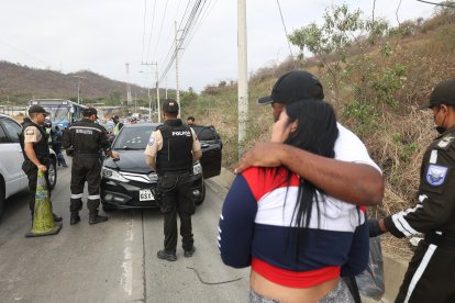 La viuda observa el procedimiento de los policías. Recibe el consuelo de sus allegados.