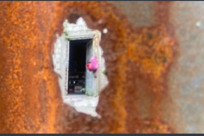 Pequeños orificios en las latas que tapan el patio que muestran parte de la propiedad.