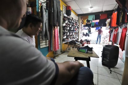 José y Víctor Zambrano, en su negocio viendo el  partido desde su teléfono.
