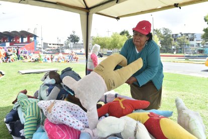 Blanca Muñoz acomoda a uno de sus muñecos sin cabeza frente a su puesto de venta.