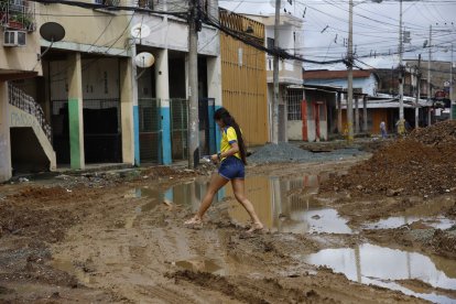 Las personas tratan de sortear el lodo al salir de sus casas. Eso es difícil, por lo que a veces salen en zapatillas y llevan los zapatos guardados.