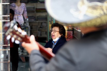 Rina de Rodríguez canta a viva voz un bolero, sentada en la puerta del local de su comadre, en Bellavista Alta.