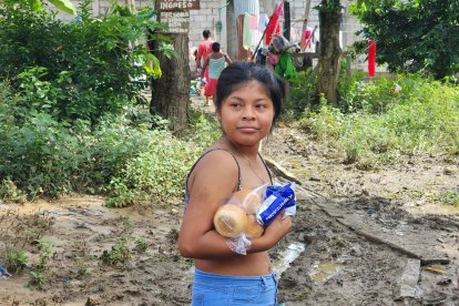 Una jovencita va con sus productos a su casa, en medio del lodo que ha quedado.