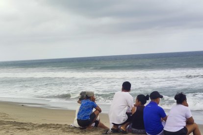 Sentados en la orilla de la playa, los deudos anhelan que su pariente aparezca.