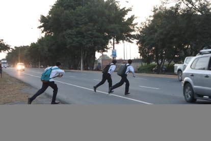Estudiantes, solos o acompañados, se acercan al filo de la vía para esperar el momento propicio para cruzar.