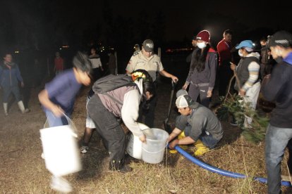 La comunidad recogía en baldes el agua para ayudar a los bomberos en la emergencia.