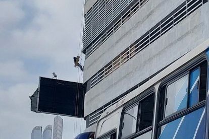 ¡Sin miedo! Un arriesgado trabajador cuelga en lo alto de un edificio, mientras coloca unas películas de protección a los vidrios en la parte externa. Una tarea que no cualquiera se atrevería a realizar.