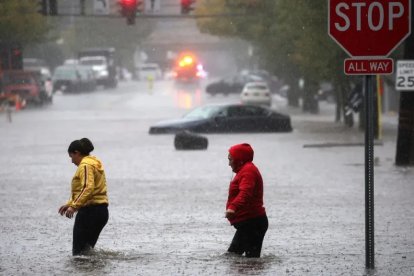 Los residentes caminan a través de las aguas de la inundación en el suburbio neoyorquino de Mamaroneck, en el condado de Westchester, Nueva York, este viernes.