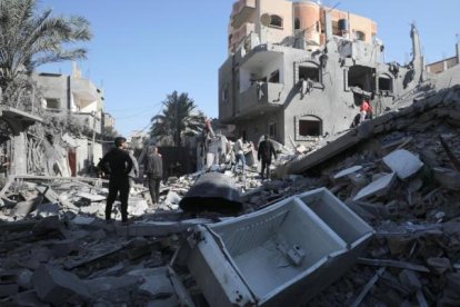 Palestinos buscan víctimas y supervivientes entre los escombros de las casas destruidas.