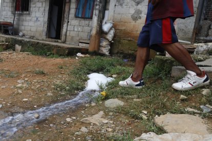 Mudumba camina sobre una filtración de agua que tiene  la calle.