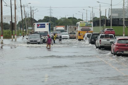 Los habitantes de Jujan ayudan a los viajeros a pasar sus vehículos con seguridad en las zonas inundadas.