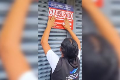 Funcionaria de Arcsa coloca el sello de clausura en la puerta de un supermercado en Ibarra.