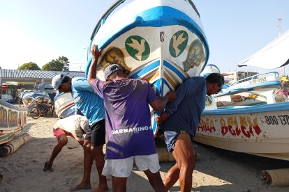 Entre 4 forzudos bajan los botes hacia el mar, para que los pescadores inicien su jornada diaria.