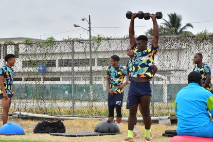 Aris Mina realiza los ejercicios con pesas en el mismo campo de juego que realizan fútbol.