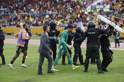 El arquero Víctor Mendoza es protegido por la policía al dirigirse al camerino.