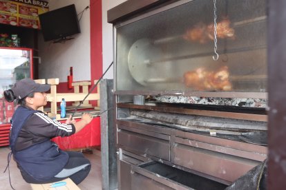 Josselyn Andrango pone en funcionamiento el rosticero de los pollos con sus manos.