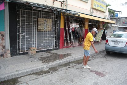 Un morador señala la sangre que quedó en el exterior del negocio donde ocurrió el ataque.