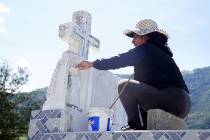 Margot Vaca arregla la tumba de su bisabuelo, quien donó el terreno para el cementerio.