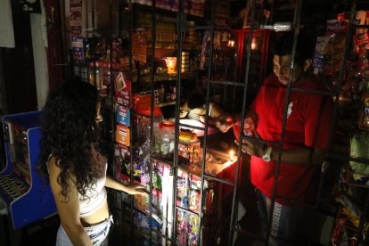 Fausto Bohórquez atiende su negocio con un par de velas.
