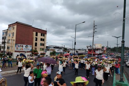 Unas voluntarias recogen flores y las llevan en la cabeza para luego ponerlas frente a las imágenes