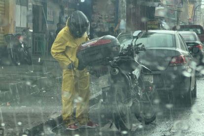 Un motorizado, en Guayaquil, se prepara para protegerse de la lluvia.