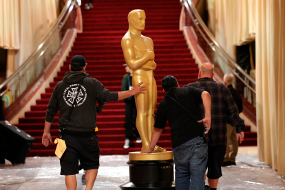 Trabajadores transportan una estatua del Oscar en la alfombra roja durante los preparativos para la 97a ceremonia anual de los Premios de la Academia.