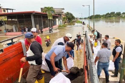 Colocando sacos con arena procuran contener la fuerza del río Vinces.