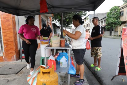 Su suegra, vestida con camiseta blanca, la ayuda en el negocio.