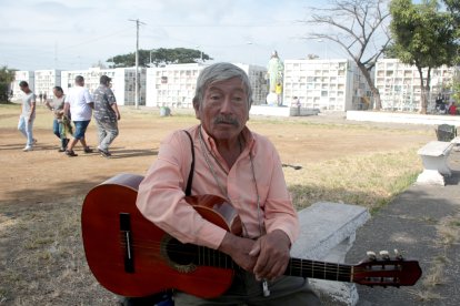 Pastor Sánchez sosteniendo su guitarra, esperando que alguien lo contrate para cantarle a los muertitos.