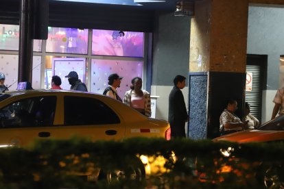 Una gran cantidad de personas esperan taxi al pie del local de juegos de azar.