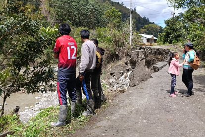 En Loja, la gente mira cómo el agua crece y destruye carreteras.