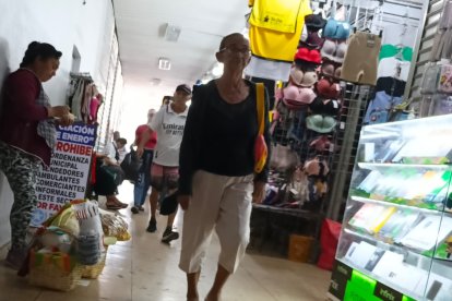 Una vendedora informal ignora un cartel que prohíbe expresamente el comercio ambulante en esa zona.