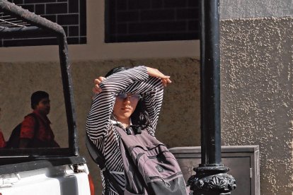 Los peatones se cubren con lo que pueden del cegador resplandor vespertino.