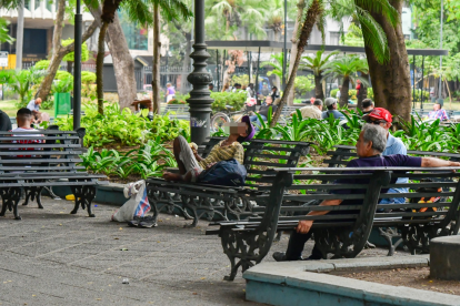 Foto de octubre de 2023. Un hombre en condición de calle duerme en una de las bancas metálicas del parque.