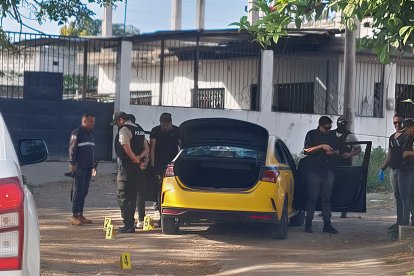 Personal de la Policía y Criminalística buscan indicios en el taxi donde fue baleado el joven conductor.