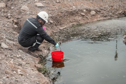 Una persona recoge el agua contaminada del río Daule.
