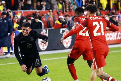 Kendry Páez (i) no logra superar la férrea marca de los defensores canadienses.