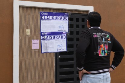 Ciudadano lee los adhesivos de clausura pegados en los exteriores de la propiedad.