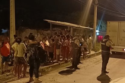 Curiosos observan el trabajo policial en el sector Lucha de los Pobres, donde un volcamiento dejó a un joven fallecido.