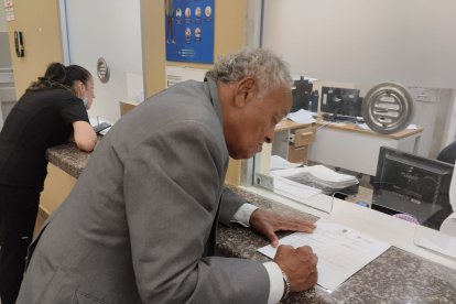 El hombre mientras firma la documentación necesaria para completar el proceso.