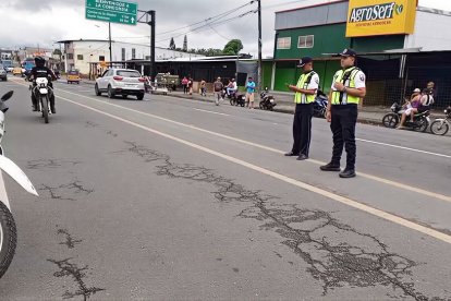 Agentes de tránsito controlan el ingreso a La Concordia, en la vía principal, mientras vehículos y motociclistas circulan bajo supervisión policial.
