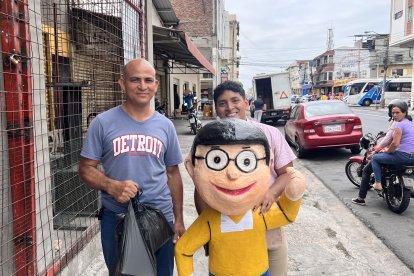 Andrés Medina (azul) junto a un pana posan con el monigote de Nobita recién comprado.