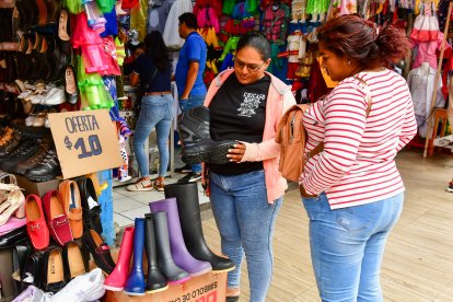 Vendedora muestra las botas de motociclista para lluvia que se exhiben en NYA Calzado.