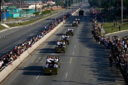 Ciudadanos observan la caravana que transporta los restos de los oficiales cubanos fallecidos.
